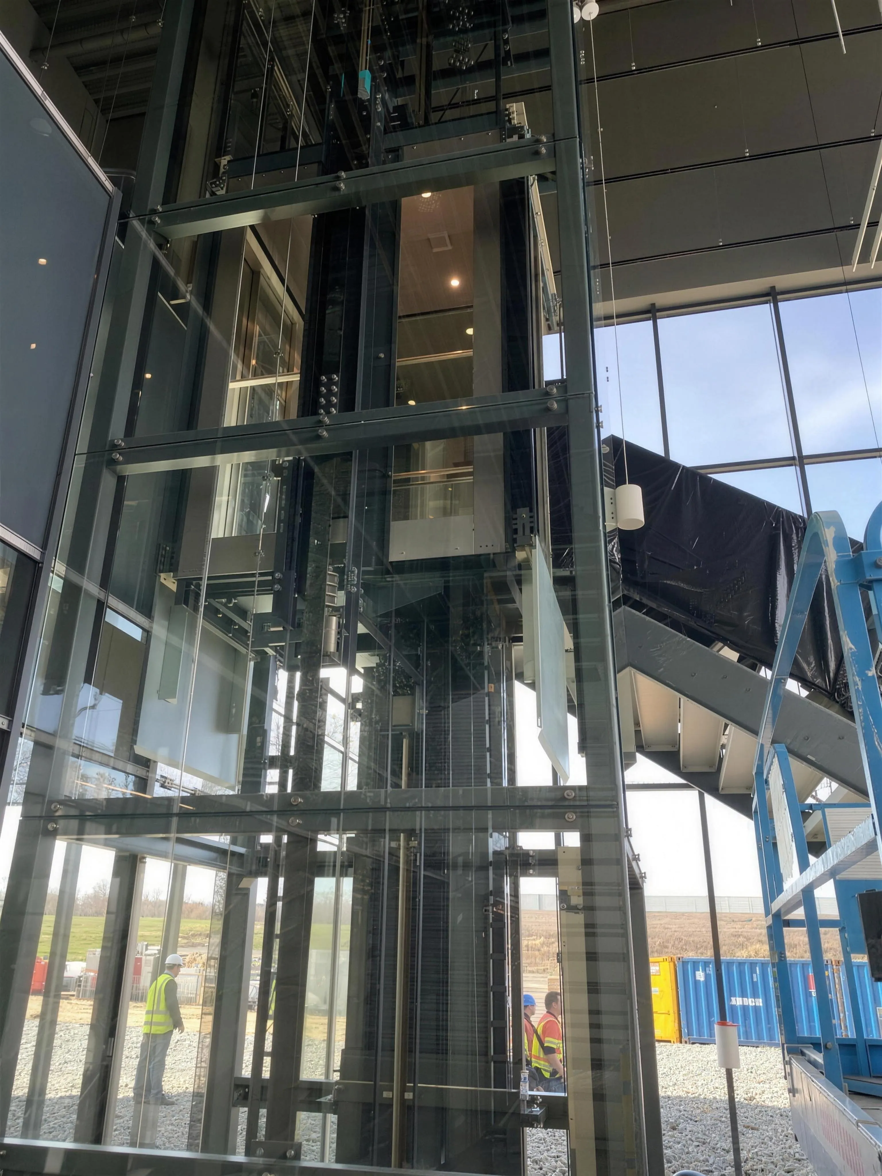 Mechanizm windy za szkłem: liny, prowadnice i rama kabiny w stalowej konstrukcji szybu
